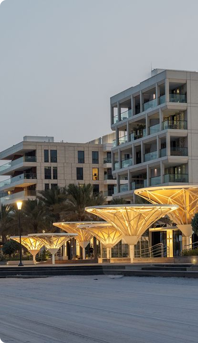 Waterfront residential buildings and an illuminated promenade at dusk